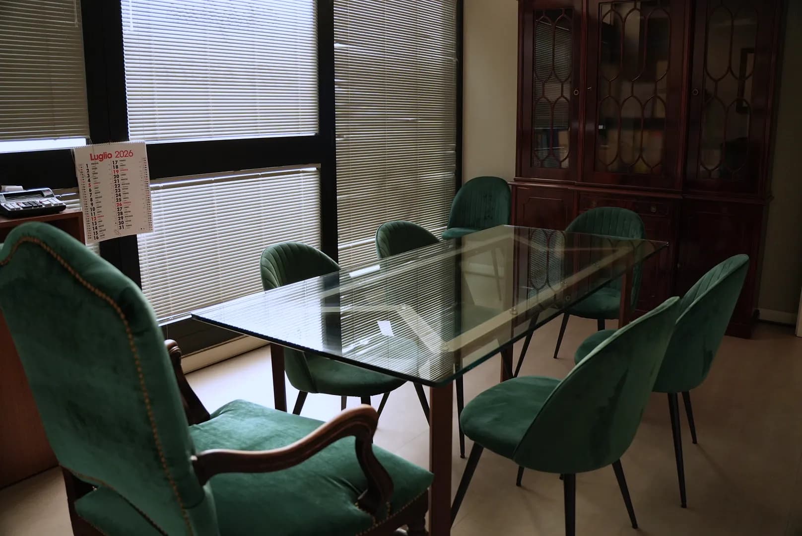 Sala riunioni con tavolo in vetro e poltroncine in velluto verde