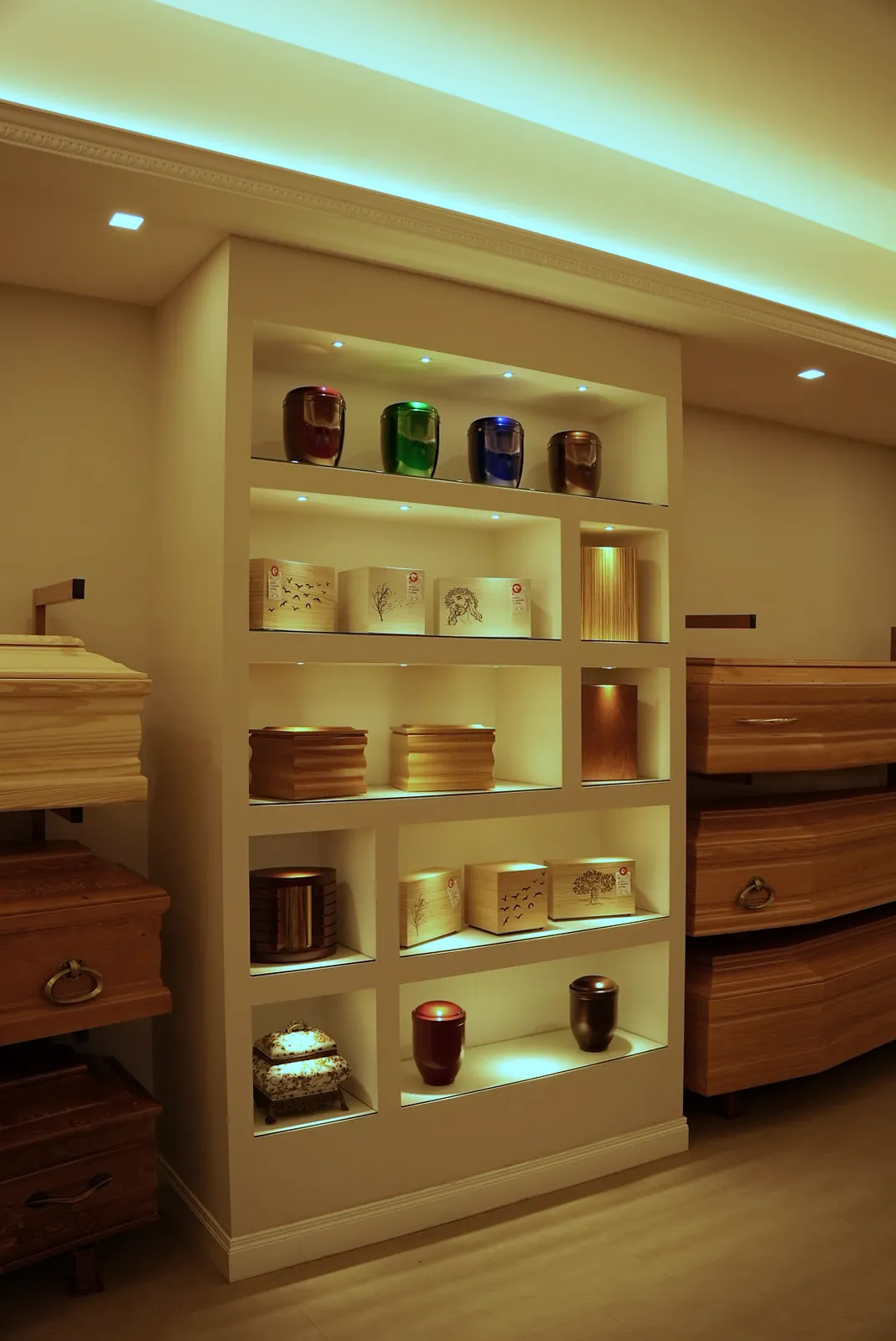 Urne cinerarie in ceramica, vetro e legno esposte nelle nicchie illuminate