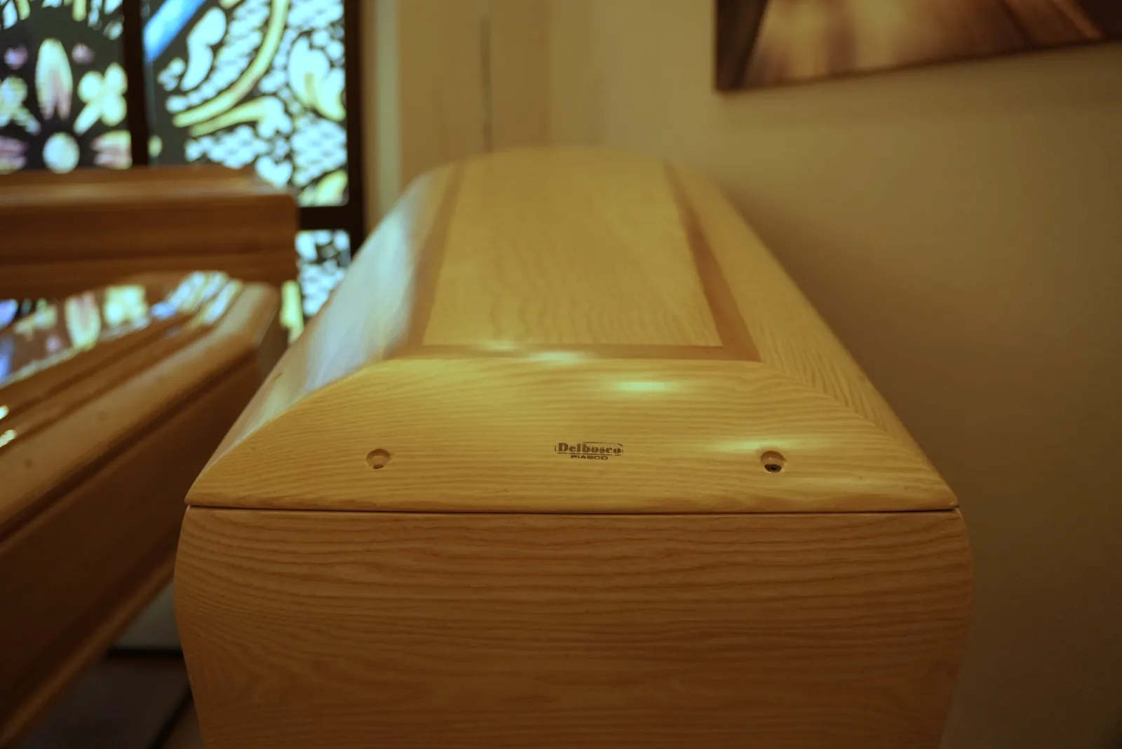 Dettaglio delle finiture di un cofano in legno accanto alla vetrata colorata