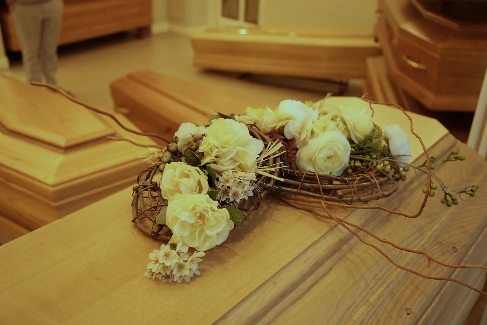 Composizione floreale di rose bianche appoggiata su un cofano in legno chiaro
